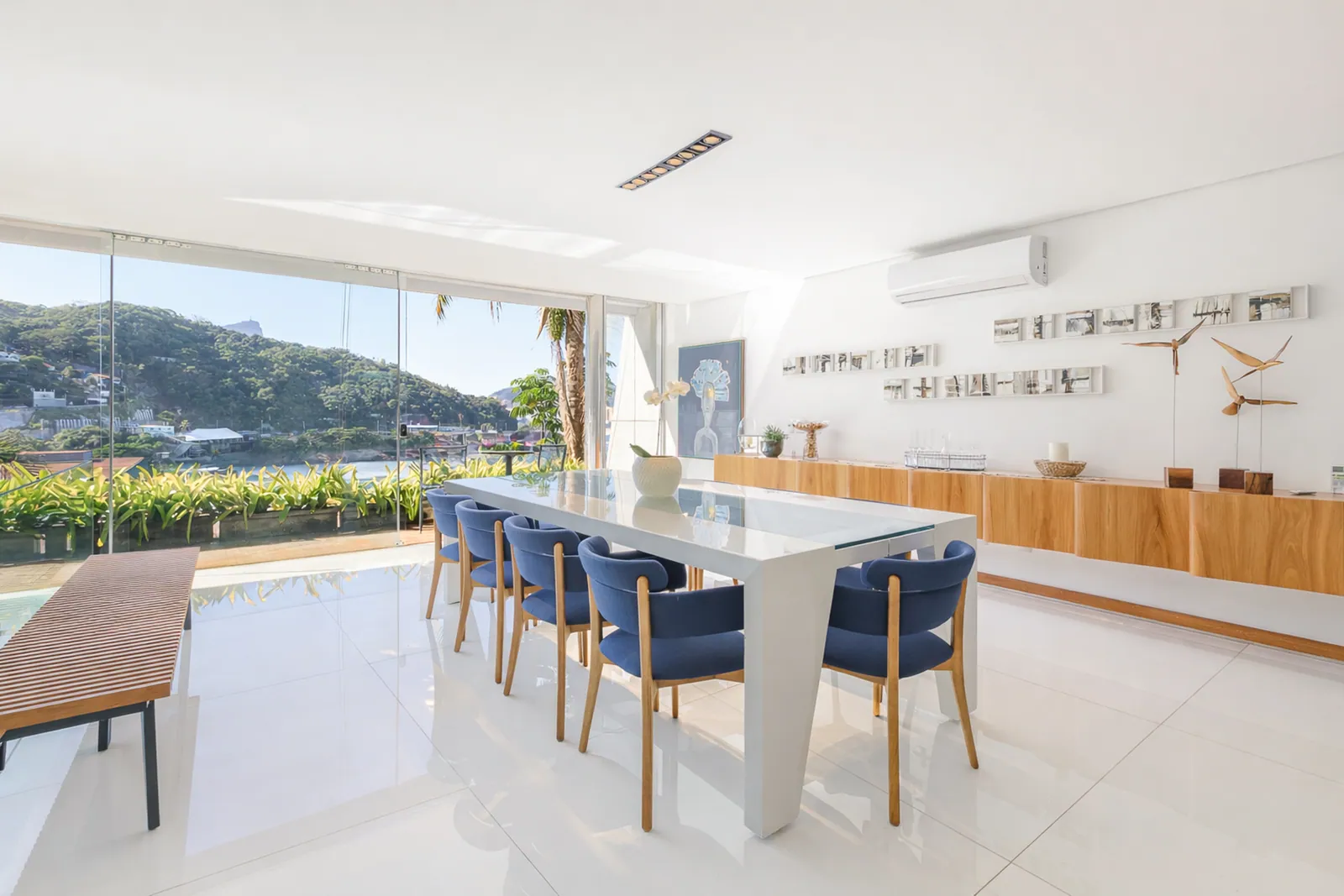The dining table beside the glass, garden and pool beyond