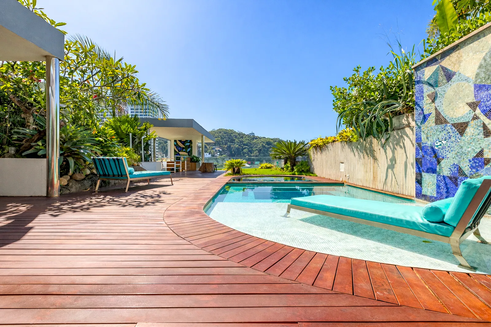 The pool on its wooden deck, mosaic wall along one side