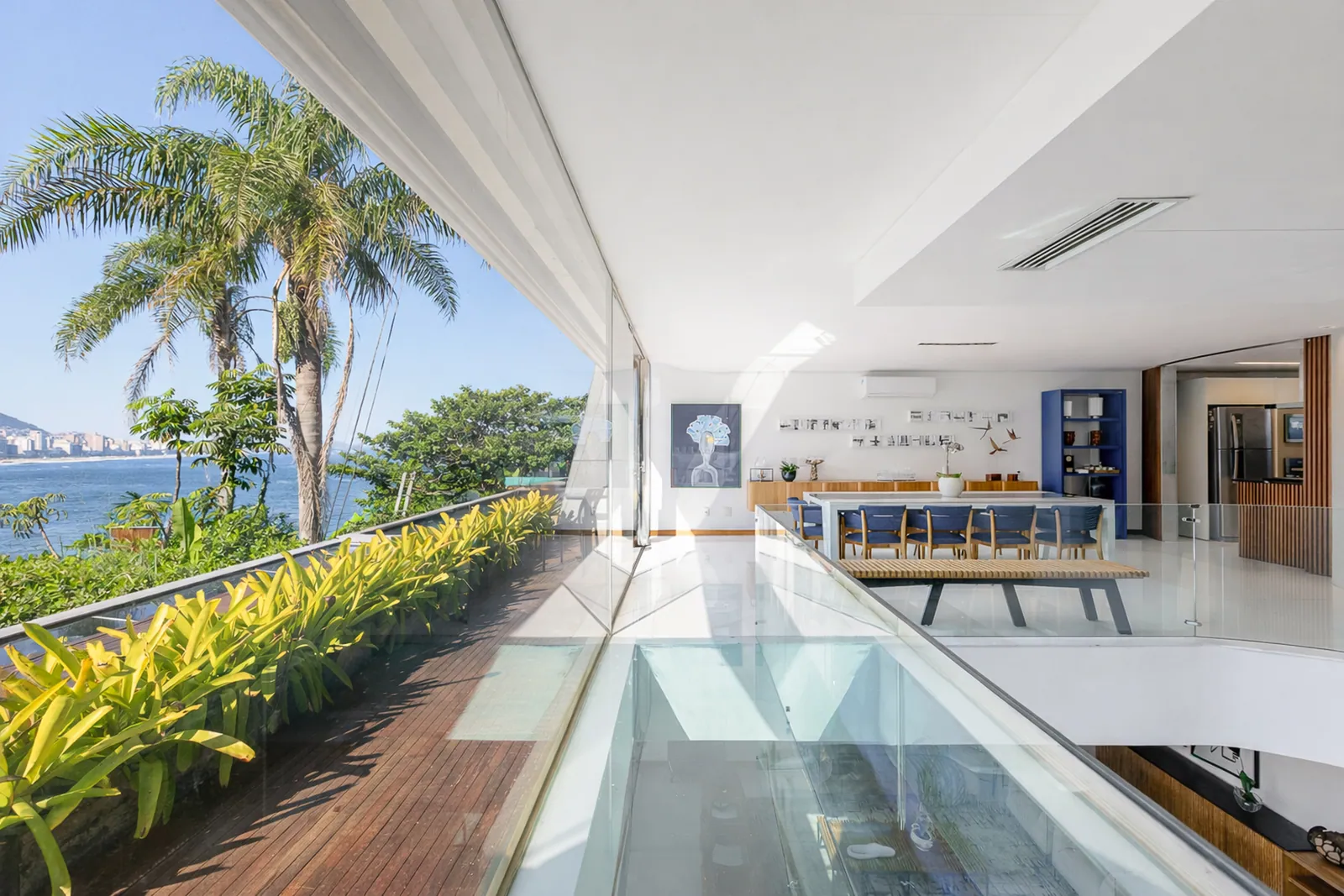 A glazed walkway over the water, palms on either side