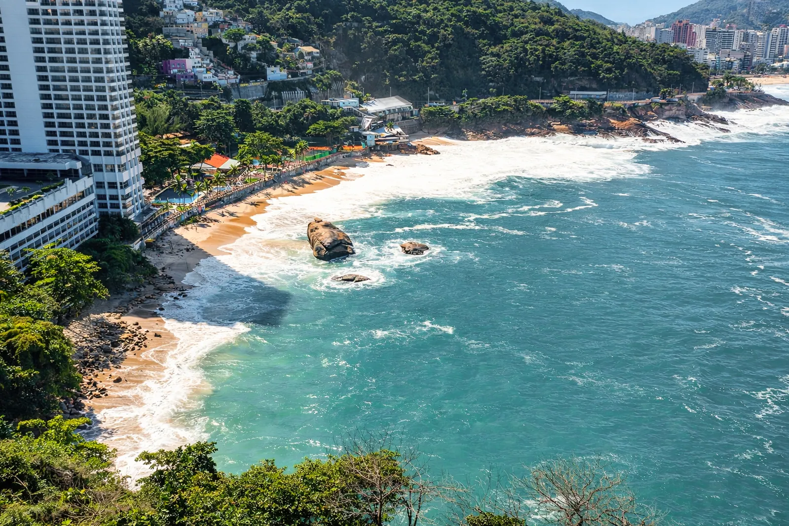 The cove and its beach from the air, rocks along the water