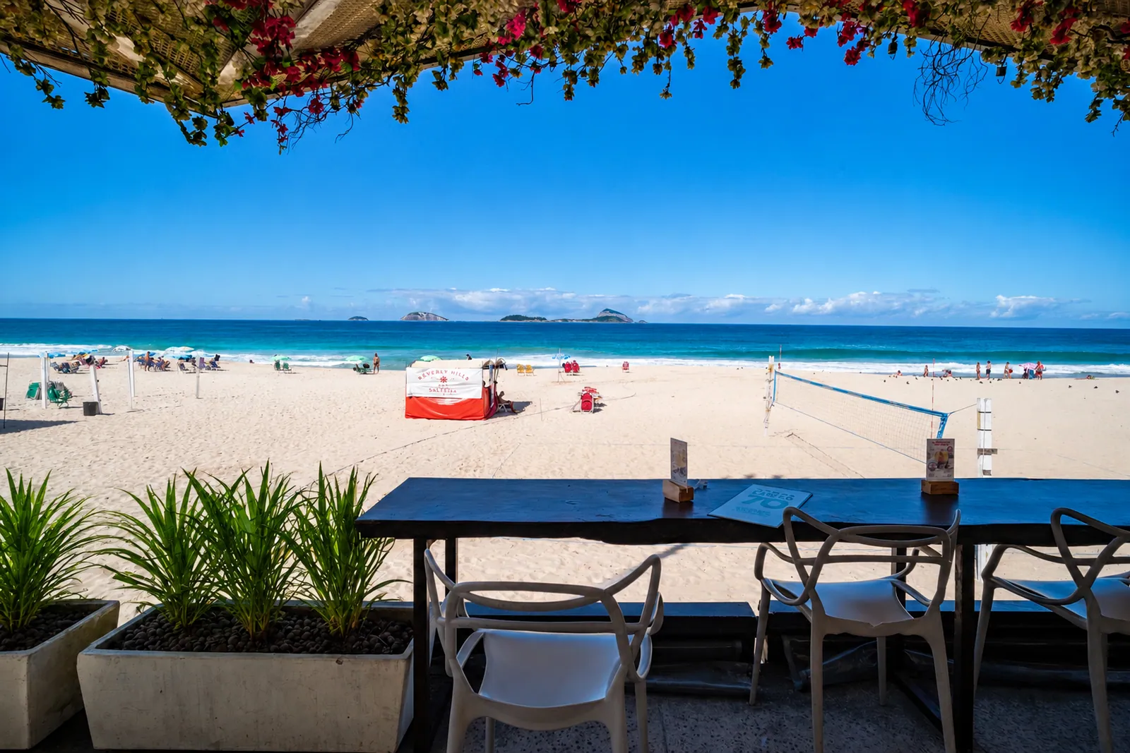 The beach seen from a restaurant terrace, bougainvillea overhead