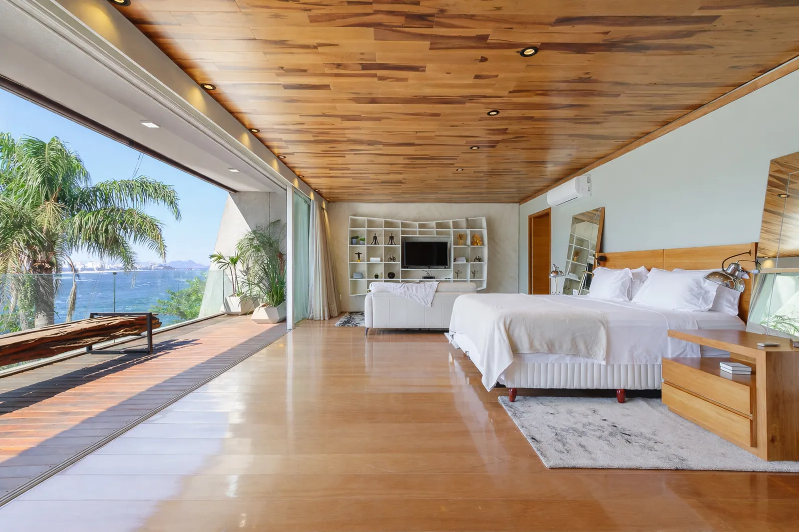 The primary suite under its wood ceiling, opening onto the terrace